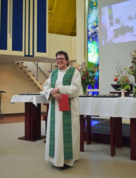 Ds. Henriette Bouwman in de kerkzaal van De Voorhof, met het glasfusieraam op de achtergrond