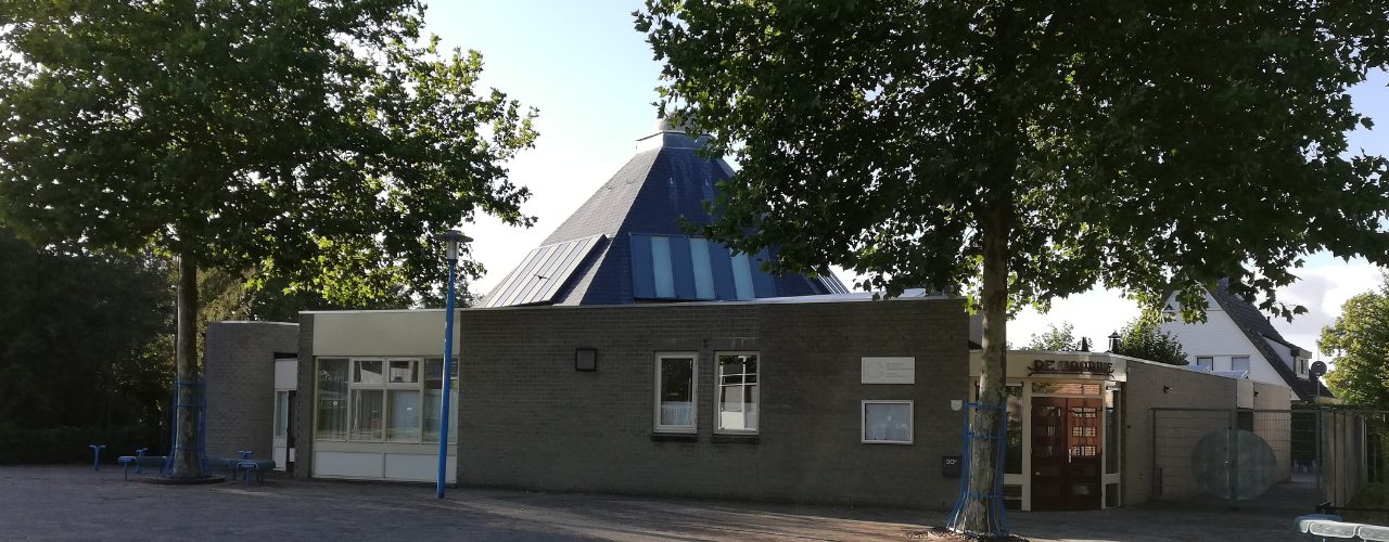 Vooraanzicht van kerkelijk centrum De Voorhof met de blauwe piramidedaken